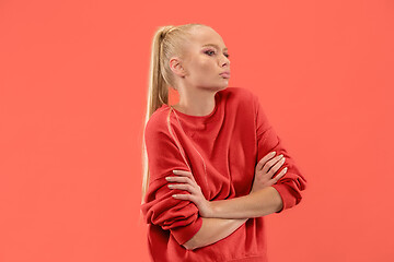 Image showing The serious business woman standing and looking at camera against coral background.