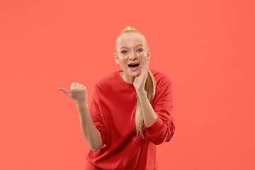 Image showing Isolated on coral young casual woman shouting at studio