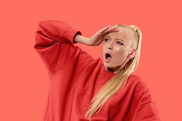 Image showing Beautiful female half-length portrait isolated on coral studio backgroud. The young emotional surprised woman