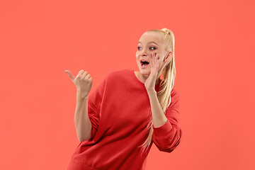 Image showing Isolated on coral young casual woman shouting at studio