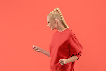 Image showing Beautiful female half-length portrait isolated on coral studio backgroud. The young emotional surprised woman