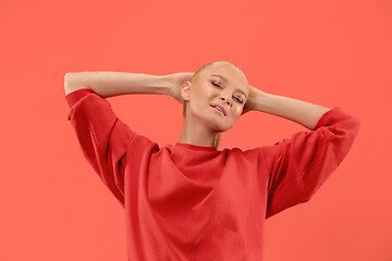 Image showing The happy business woman standing and smiling against coral background.