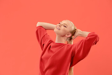 Image showing The happy business woman standing and smiling against coral background.