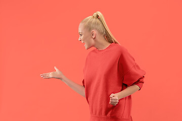 Image showing Beautiful female half-length portrait isolated on coral studio backgroud. The young emotional surprised woman