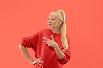 Image showing Isolated on coral young casual woman shouting at studio