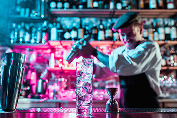 Image showing Expert barman is making cocktail at night club.