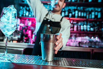 Image showing Expert barman is making cocktail at night club.