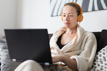 Image showing Stay at home and social distancing. Woman in her casual home bathrobe working remotly from her living room. Video chatting using social media with friend, family, business clients or partners