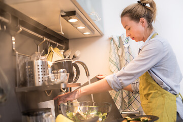 Image showing Stay at home housewife woman cooking in kitchen, stir frying dish in a saucepan, preparing food for family dinner.