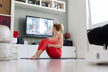 Image showing Attractive sporty woman working out at home, doing pilates exercise in front of television in her living room. Social distancing. Stay healthy and stay at home during corona virus pandemic