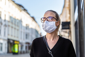 Image showing COVID-19 Pandemic Coronavirus. Young girl in city street wearing face mask protective for spreading of Coronavirus Disease 2019. Close up of young woman with medical mask on face against SARS-CoV-2