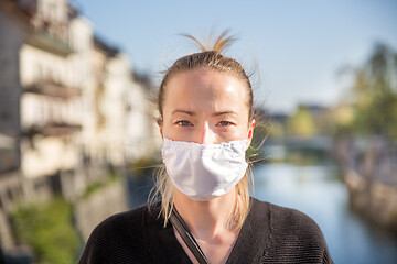 Image showing COVID-19 pandemic coronavirus. Young girl in city street wearing face mask protective for spreading of coronavirus disease 2020. Close up of young woman with medical mask on face against SARS-CoV-2