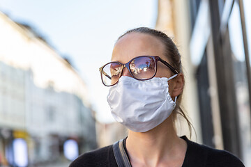 Image showing COVID-19 Pandemic Coronavirus. Young girl in city street wearing face mask protective for spreading of Coronavirus Disease 2019. Close up of young woman with medical mask on face against SARS-CoV-2