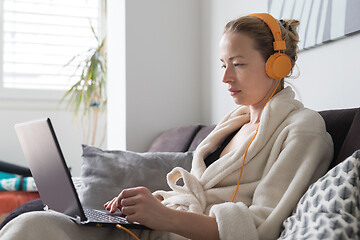 Image showing Stay at home and social distancing. Woman in her casual home bathrobe working remotly from her living room. Video chatting using social media with friend, family, business clients or partners