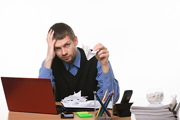 Image showing fellow sits leaning his head on his arm with crumpled sheets of paper on the table and in his other hand