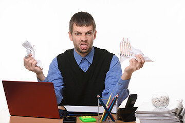 Image showing Man at work desk holds crumpled sheets of paper and shows tongue