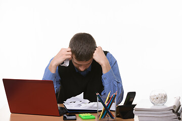 Image showing employee sits clasping his head with his fists at the office table