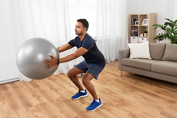 Image showing man exercising and doing squats with ball at home