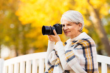 Image showing senior woman with photo camera at autumn park