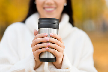 Image showing happy young woman drinking coffee in autumn park