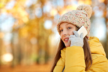 Image showing happy girl calling on smartphone at autumn park