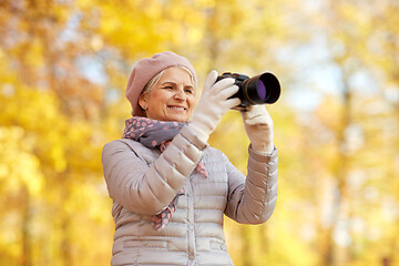 Image showing senior woman with photo camera at autumn park