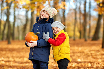 Image showing happy children with pumpkin hugging at autumn park