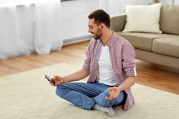 Image showing man in earphones listening to music and meditating