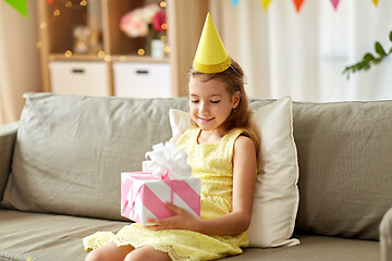 Image showing happy girl in party hat with birthday gift at home