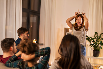 Image showing happy friends playing charades at home in evening