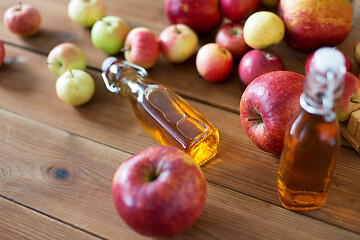 Image showing bottles of apple juice or vinegar on wooden table