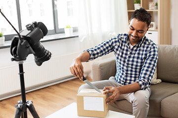 Image showing male video blogger opening parcel box at home