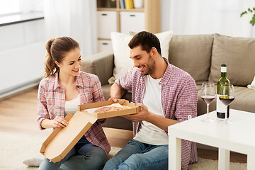 Image showing couple with wine eating takeaway pizza at home