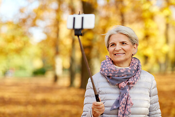 Image showing senior woman taking selfie at autumn park