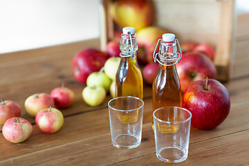 Image showing glasses and bottles of apple juice on wooden table