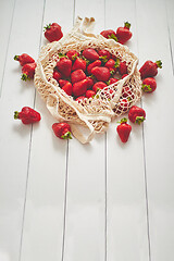Image showing Fresh strawberries in eco-friendly package on white wooden background. Vegetarian organic meal