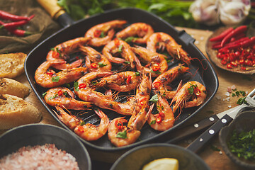 Image showing Tasty appetizing roasted shrimps prawns with spices on pan with ingredients on rusty background