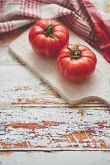 Image showing Top view of a white cutting board with a fresh juicy tomatoes on a wooden table