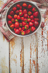 Image showing Freshly harvested strawberries. Metal colander filled with juicy fresh ripe strawberries on an table