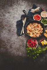 Image showing Grilled shrimps in cast iron grilling pan with fresh lemon, parsley, chili, garlic white wine sauce