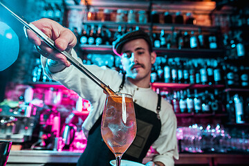 Image showing Expert barman is making cocktail at night club.