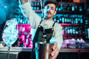 Image showing Expert barman is making cocktail at night club.