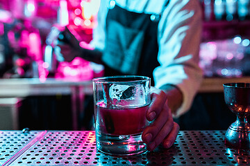 Image showing Expert barman is making cocktail at night club.