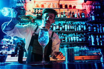 Image showing Expert barman is making cocktail at night club.