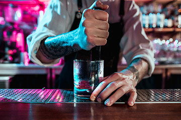 Image showing Expert barman is making cocktail at night club.