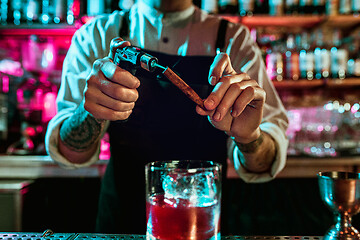 Image showing Expert barman is making cocktail at night club.