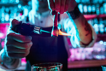 Image showing Expert barman is making cocktail at night club.