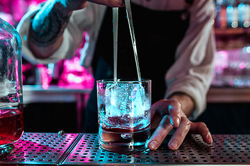 Image showing Expert barman is making cocktail at night club.