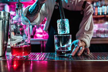 Image showing Expert barman is making cocktail at night club.