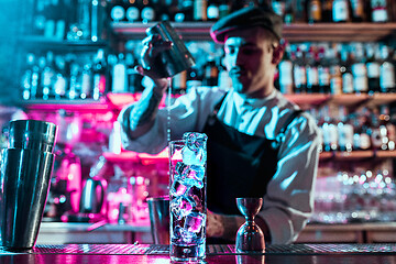 Image showing Expert barman is making cocktail at night club.